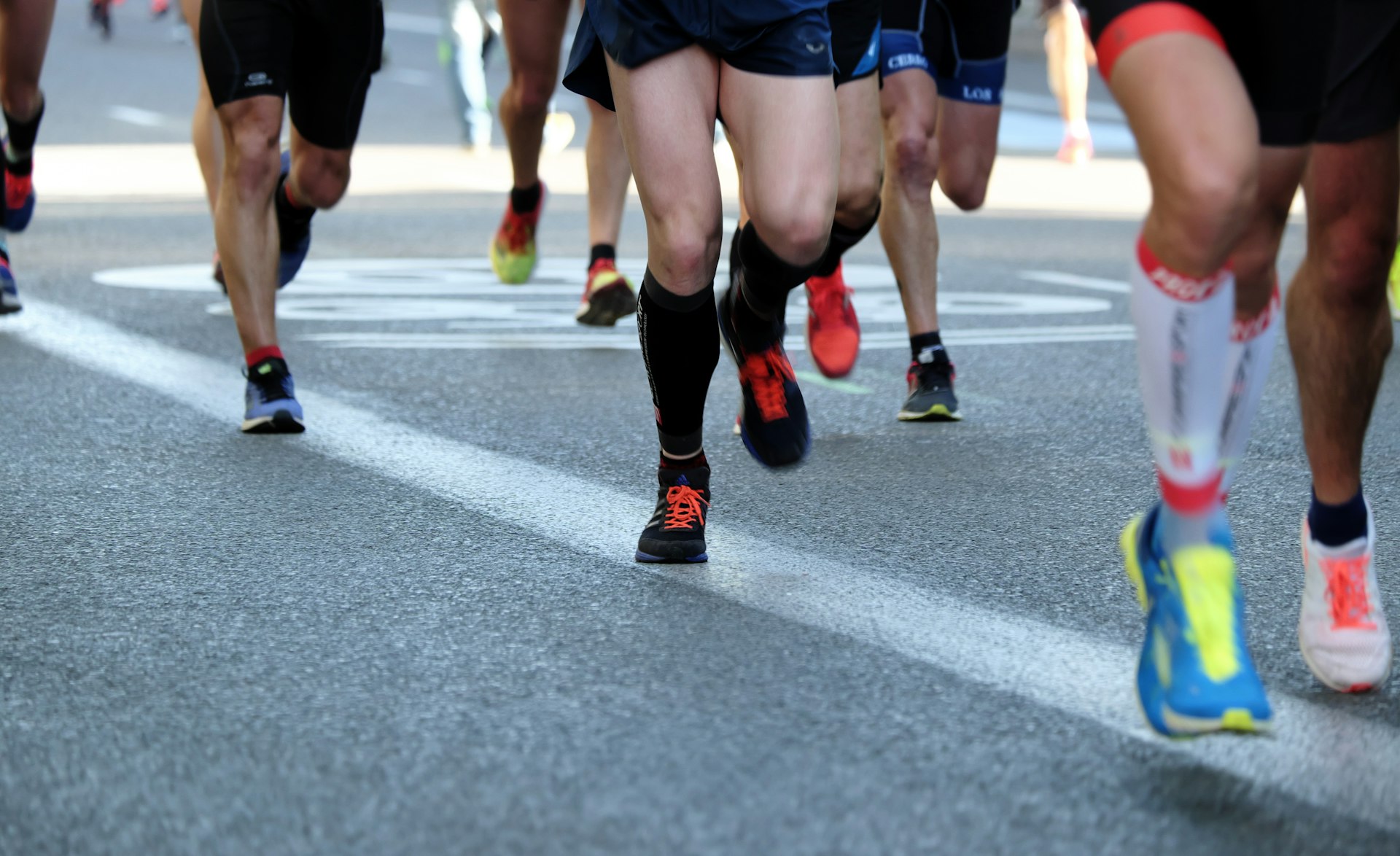 Piernas y zapatillas de un grupo de corredores en una carrera popular por carretera